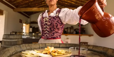 Camarera sirviendo vino para acompañar una tabla de quesos en un mesón de Puy du Fou España